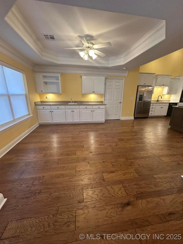 kitchen with white cabinets, stainless steel fridge, a raised ceiling, and sink