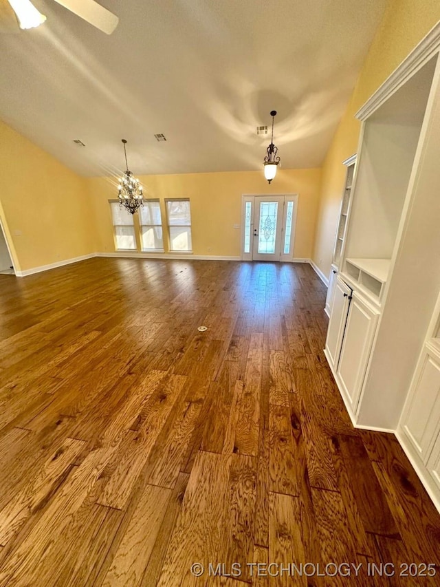 unfurnished living room with built in shelves, a chandelier, and dark hardwood / wood-style floors