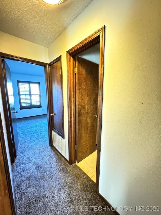 hall featuring carpet and a textured ceiling