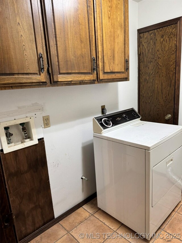 washroom featuring washer / clothes dryer, light tile patterned flooring, and cabinets