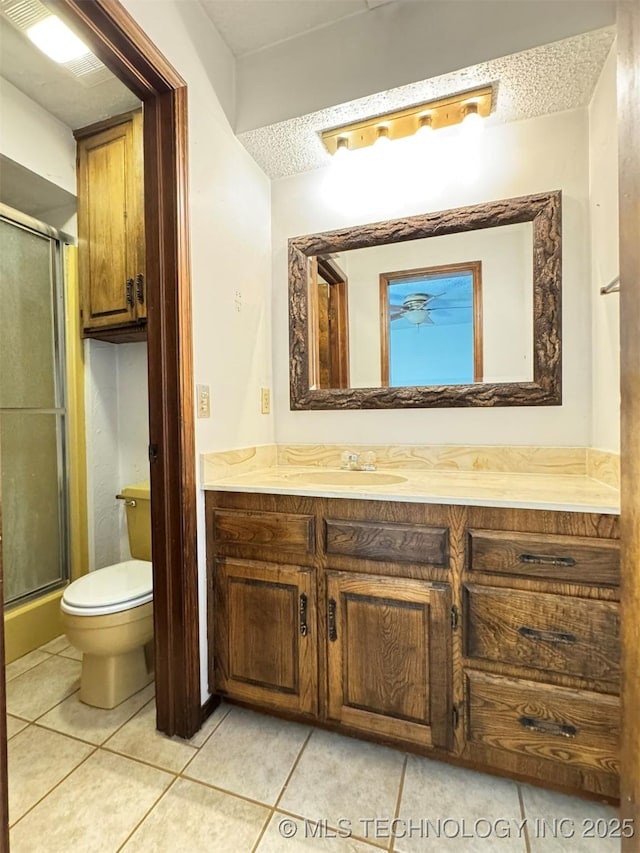 bathroom with tile patterned flooring, a textured ceiling, vanity, and toilet