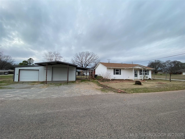 single story home featuring covered porch, an outbuilding, and a garage