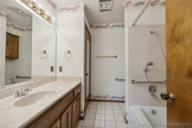 bathroom featuring tile patterned floors, vanity, tiled shower / bath, and a textured ceiling