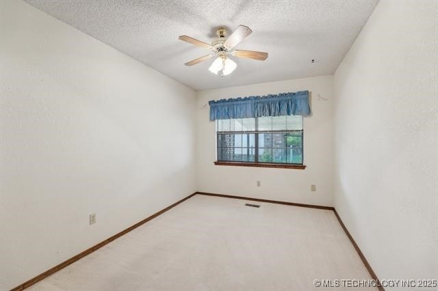 carpeted empty room with ceiling fan and a textured ceiling