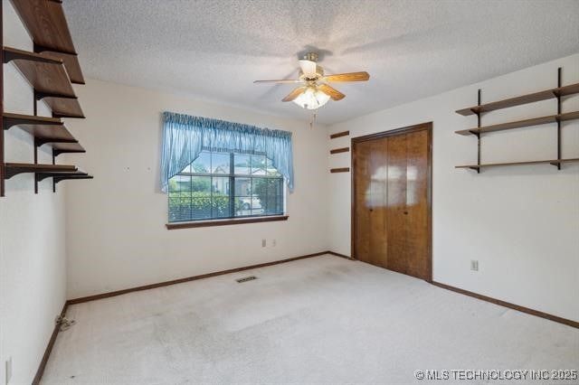 spare room featuring a textured ceiling, light colored carpet, and ceiling fan