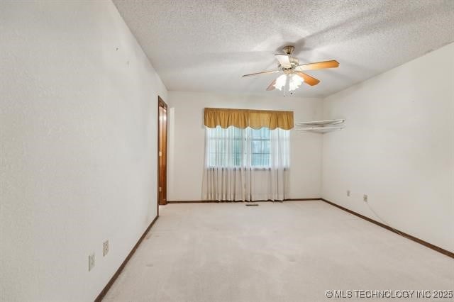 carpeted empty room with ceiling fan and a textured ceiling