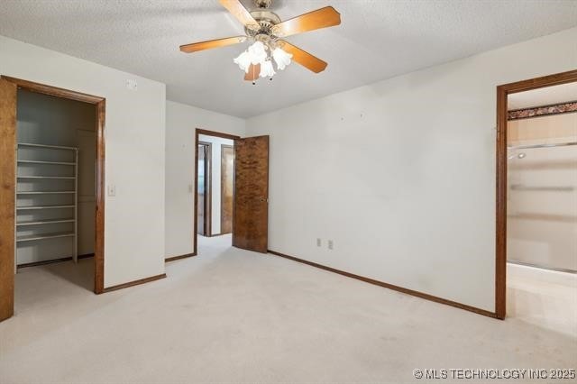 unfurnished bedroom with light carpet, a textured ceiling, a closet, and ceiling fan