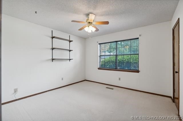 carpeted empty room with ceiling fan and a textured ceiling