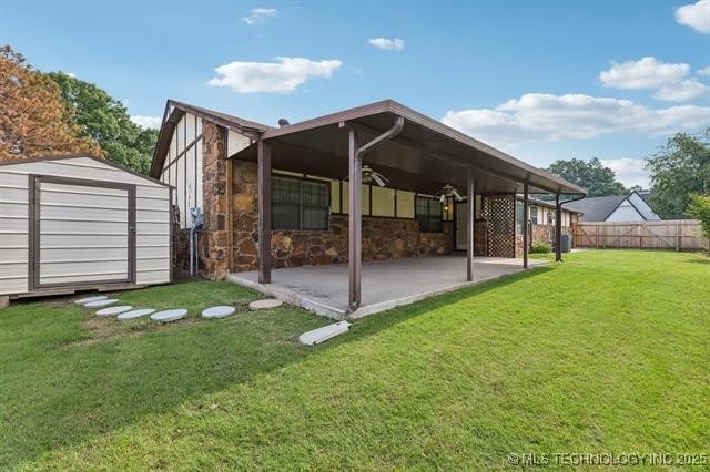 back of house with a lawn, a patio, and a storage unit