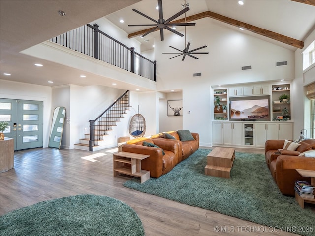 living room with ceiling fan, light hardwood / wood-style floors, a towering ceiling, and french doors