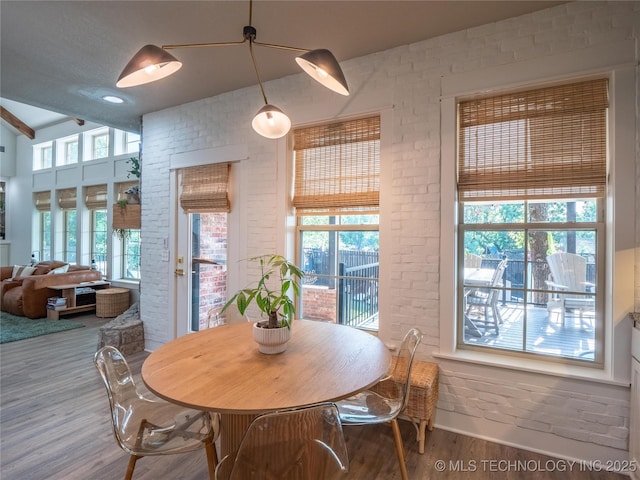 dining room with wood-type flooring and brick wall