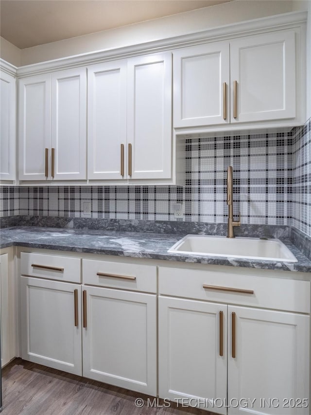 kitchen featuring tasteful backsplash, white cabinetry, sink, and hardwood / wood-style flooring