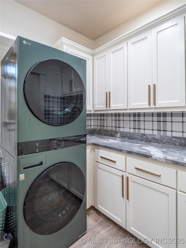 washroom with light hardwood / wood-style floors, cabinets, and stacked washing maching and dryer