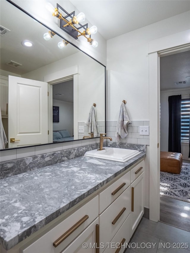 bathroom featuring tile patterned flooring, vanity, and backsplash