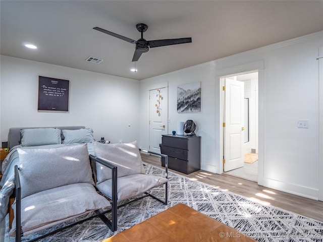 bedroom with connected bathroom, hardwood / wood-style flooring, ceiling fan, and ornamental molding