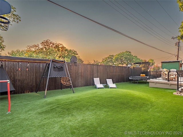 yard at dusk with a trampoline and a deck