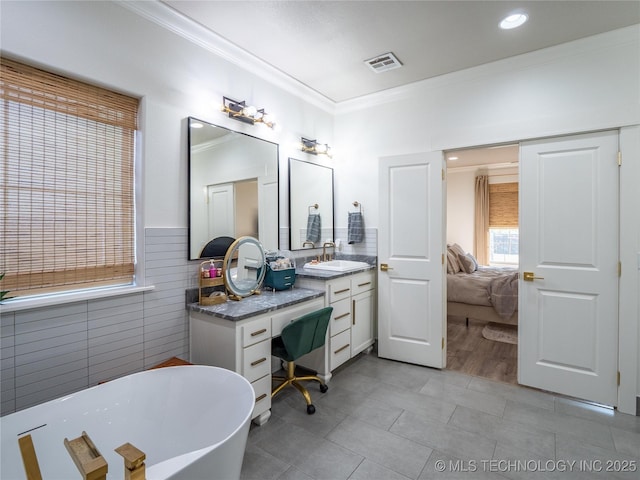 bathroom featuring vanity, a bath, crown molding, and tile walls