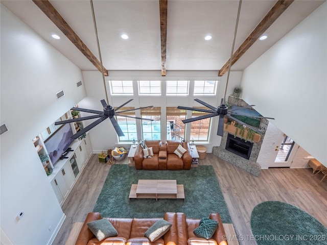 living room featuring beam ceiling, light hardwood / wood-style flooring, and ceiling fan