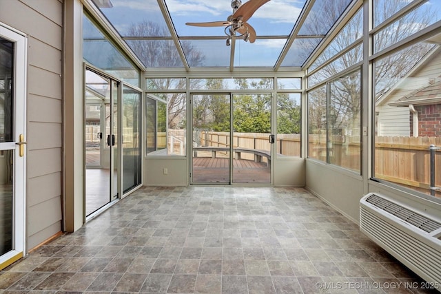 unfurnished sunroom featuring ceiling fan and a wall mounted air conditioner