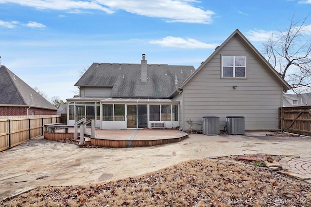 rear view of property with a deck, a sunroom, and central AC