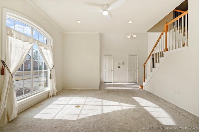 carpeted entrance foyer with ceiling fan with notable chandelier and ornamental molding