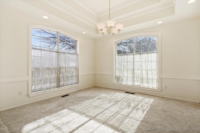 unfurnished room featuring ornamental molding, an inviting chandelier, carpet flooring, and a raised ceiling