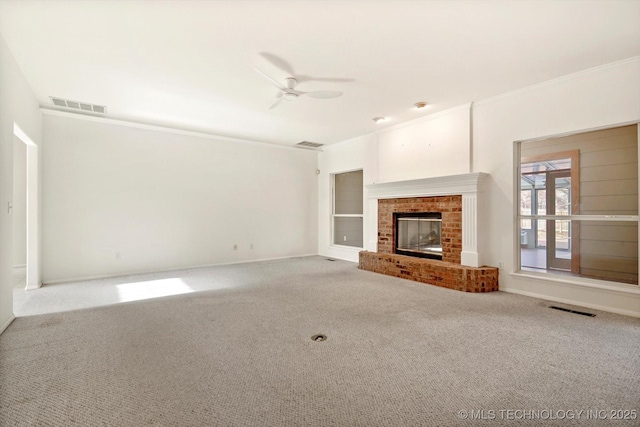 unfurnished living room with ceiling fan, ornamental molding, carpet floors, and a fireplace