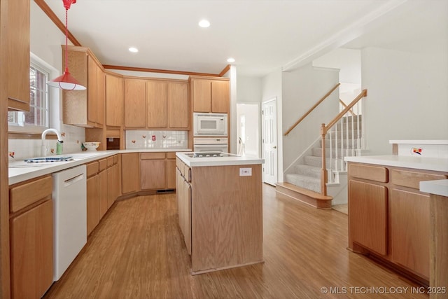 kitchen with sink, light brown cabinets, white appliances, and a center island