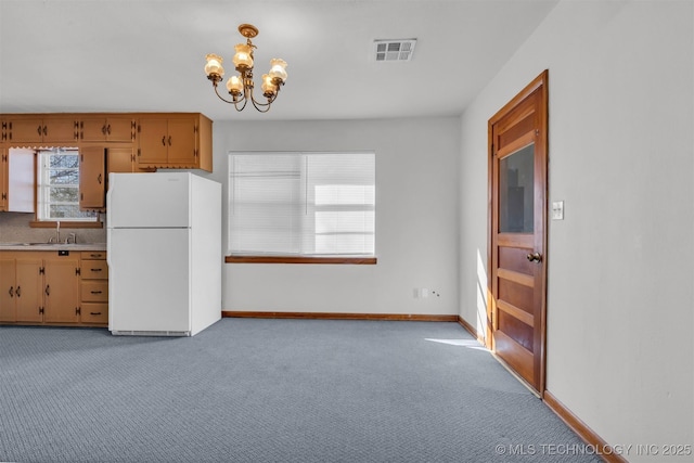 kitchen with pendant lighting, white refrigerator, tasteful backsplash, light carpet, and a chandelier