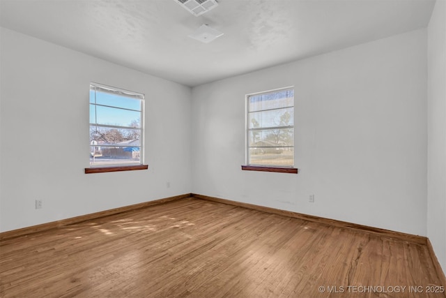 spare room with plenty of natural light and hardwood / wood-style floors