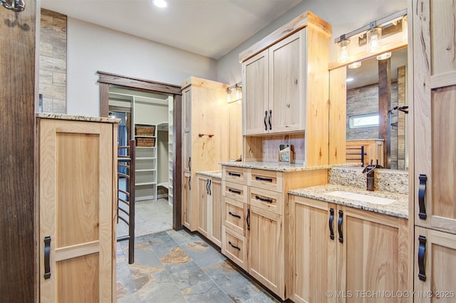 interior space featuring light brown cabinetry, sink, and light stone countertops