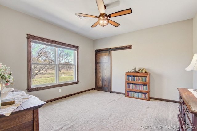 interior space with ceiling fan, a barn door, and light colored carpet