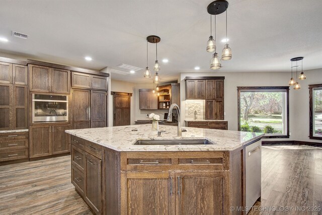 kitchen with pendant lighting, stainless steel appliances, sink, and a large island with sink