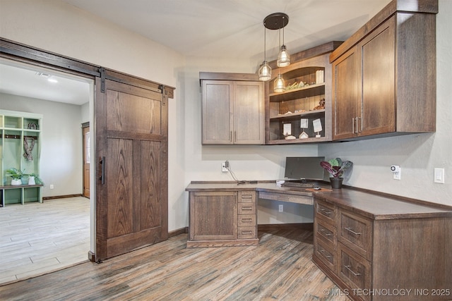 office space with a barn door, built in desk, and light hardwood / wood-style floors