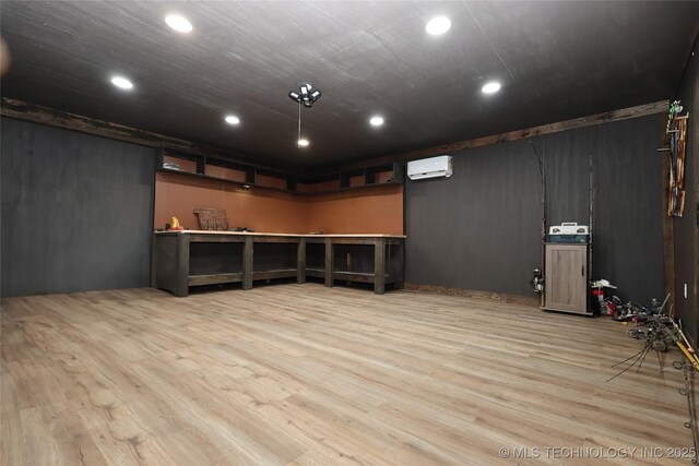 basement with a wall mounted air conditioner and light hardwood / wood-style flooring