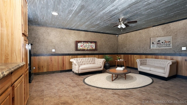 sitting room with wooden walls and ceiling fan