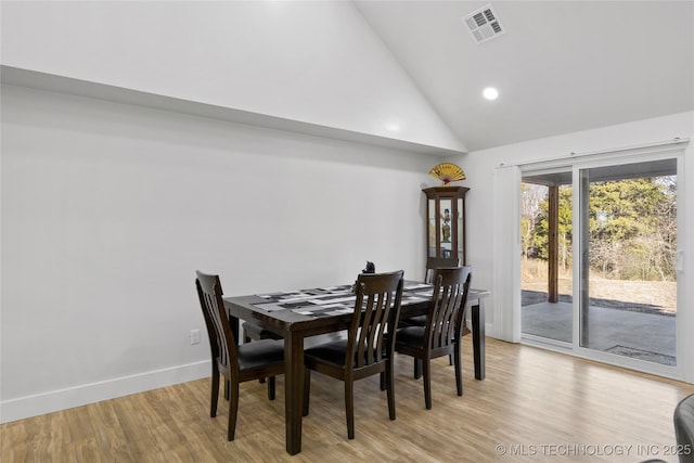 dining room featuring high vaulted ceiling and light hardwood / wood-style flooring