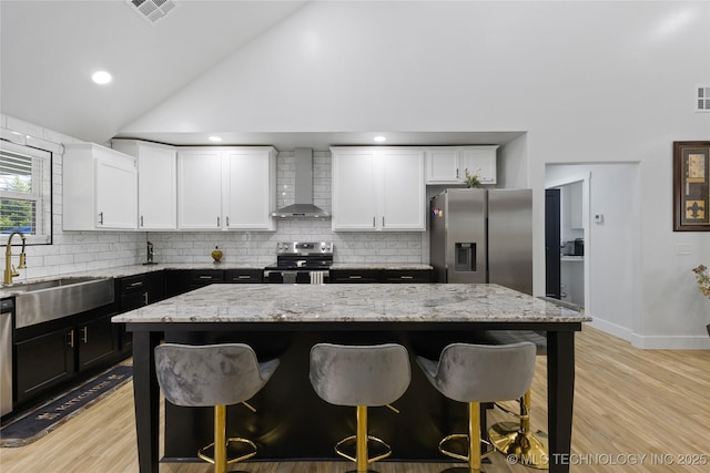 kitchen with a center island, wall chimney range hood, and stainless steel appliances