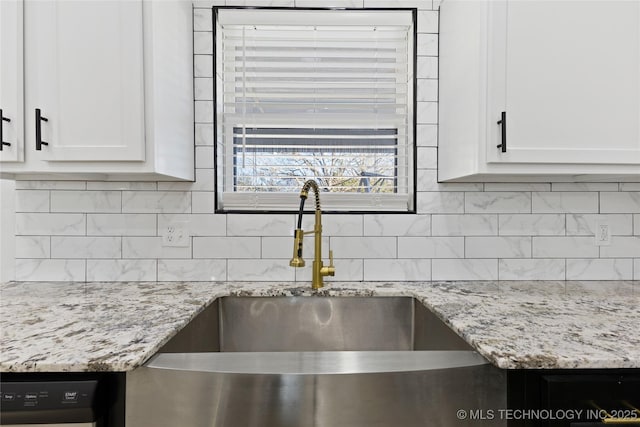 kitchen featuring decorative backsplash, white cabinetry, sink, and light stone counters