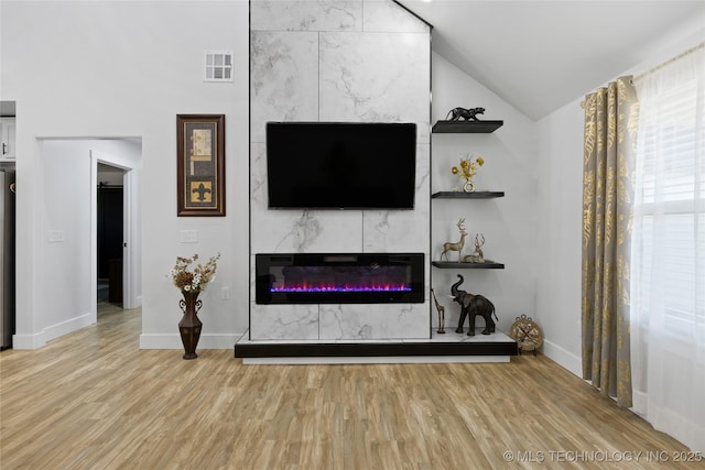 living room with a high end fireplace, wood-type flooring, and lofted ceiling