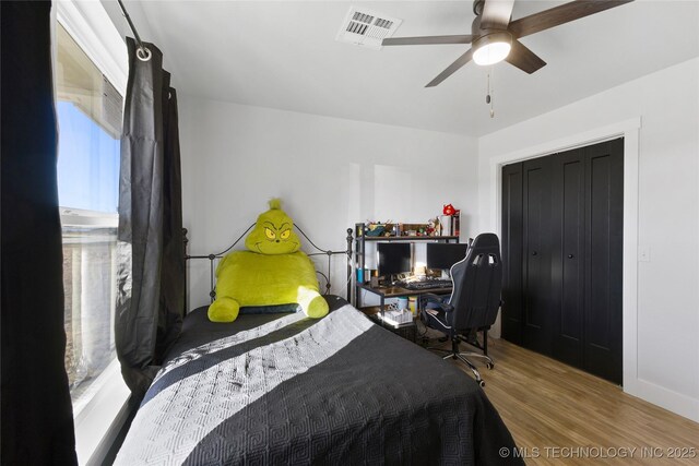 bedroom with hardwood / wood-style flooring, ceiling fan, a closet, and multiple windows