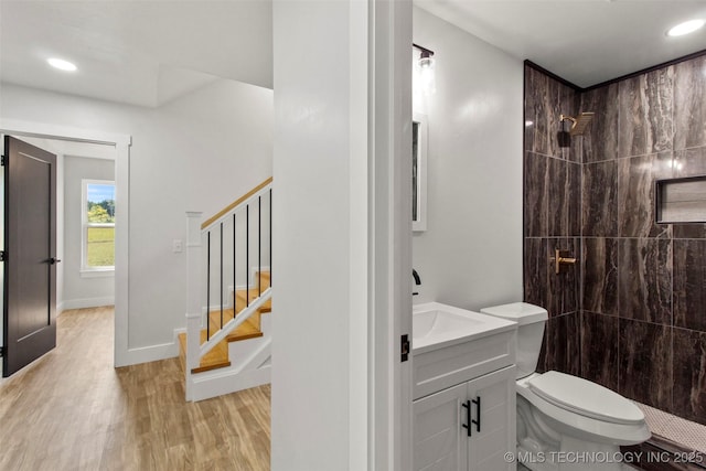 bathroom with toilet, hardwood / wood-style floors, vanity, and tiled shower