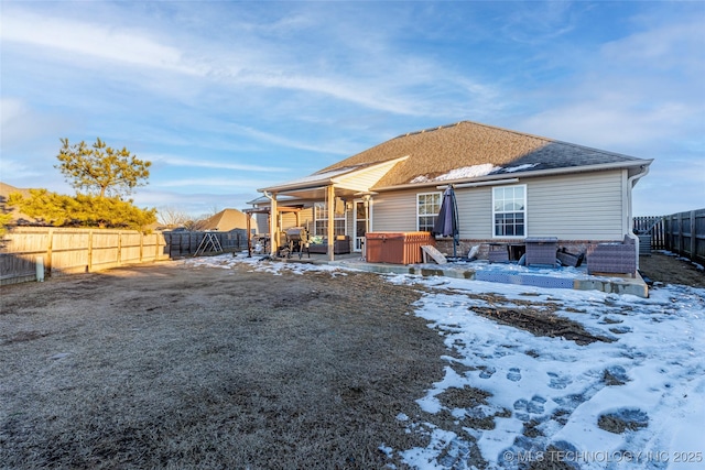 snow covered back of property featuring a hot tub