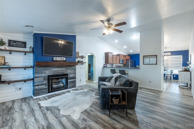 living room with ceiling fan with notable chandelier, wood-type flooring, and lofted ceiling