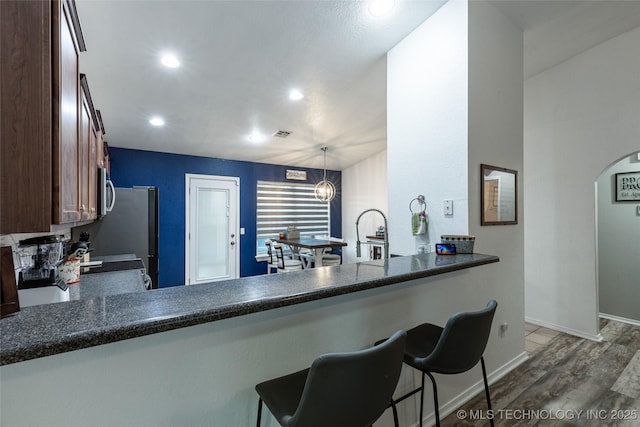 kitchen featuring kitchen peninsula, dark wood-type flooring, decorative light fixtures, and an inviting chandelier