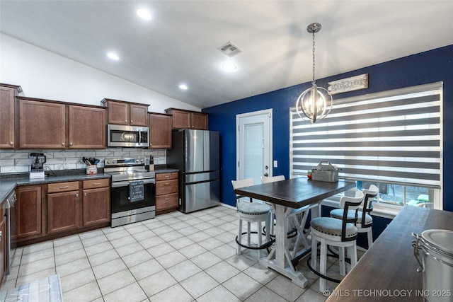 kitchen with stainless steel appliances, tasteful backsplash, pendant lighting, lofted ceiling, and a breakfast bar area