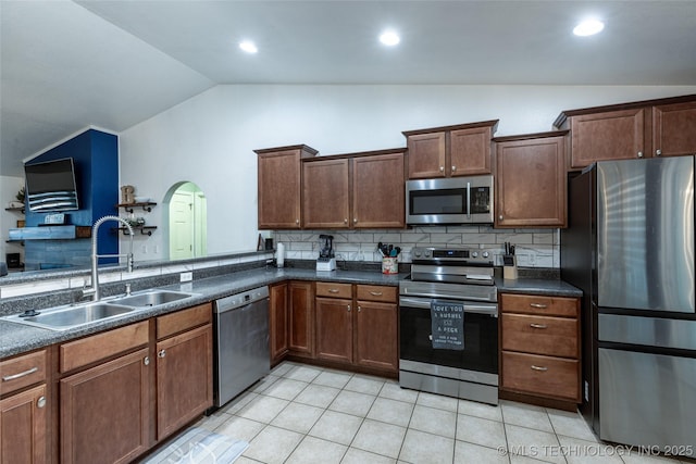 kitchen with sink, stainless steel appliances, backsplash, kitchen peninsula, and vaulted ceiling