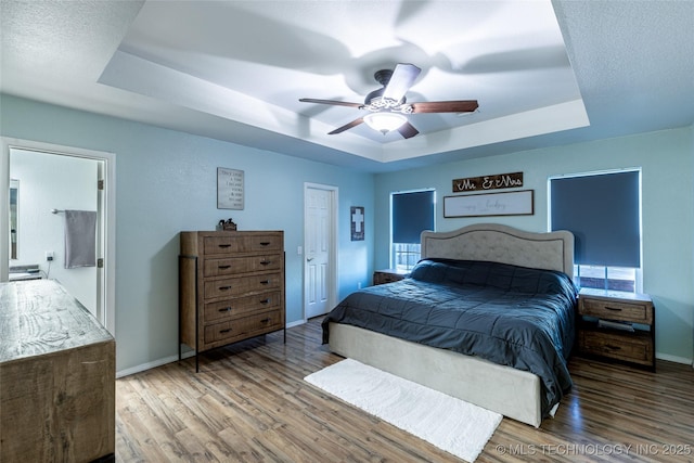 bedroom featuring hardwood / wood-style flooring, ceiling fan, and a raised ceiling