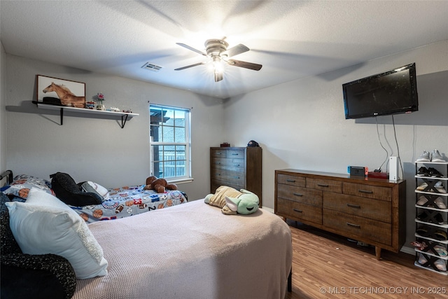 bedroom featuring ceiling fan, light hardwood / wood-style floors, and a textured ceiling