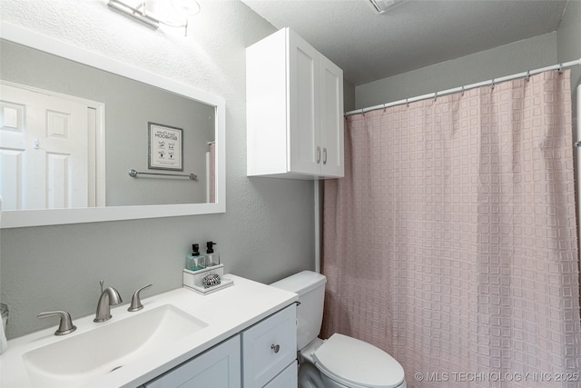 bathroom featuring vanity, a textured ceiling, and toilet